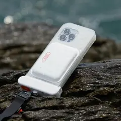 Coque étanche pour téléphone, conforme à la norme IPX8, posée sur des rochers mouillés près de la mer.