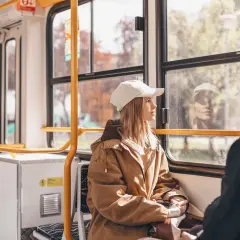 Dans un train, une jeune femme au bonnet blanc regarde par la fenêtre. Le paysage défile, rappelant un voyage en Cantal.