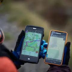 Deux smartphones affichent des cartes topographiques, un **GPS piéton** sur un iPhone et un autre appareil. Idéal pour la randonnée.