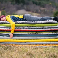 Un homme dort sur une pile de matelas gonflables. Il semble qu'il ait attendu longtemps pour savoir combien de temps laisser gonfler un matelas.