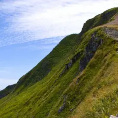 Sentier de montagne verdoyant avec escaliers, idéal pour une randonnée gr pour débutant. Paysage spectaculaire sous un ciel bleu.