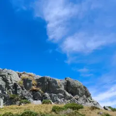 Rochers escarpés du Puy de Niermont sous un ciel bleu éclatant, parsemé de nuages légers.