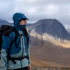 Un randonneur en tenue imperméable et sac à dos, prêt à affronter la nature sauvage pour une randonnée de plusieurs jours.