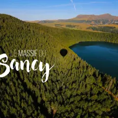 Vue aérienne du lac Estivadoux, niché au cœur du Massif du Sancy, avec une ombre de montgolfière sur la forêt.