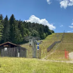 Remontée mécanique au col de Supeyres, avec une cabane en bois et une piste d'été bordée de sapins.