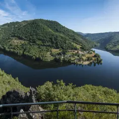 Vue panoramique des gorges de la Truyère, un lac paisible serpente entre des collines verdoyantes. Idéal pour la randonnée.