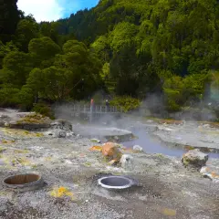 Paysage volcanique des Furnas Açores, avec des fumerolles et des sources chaudes au milieu d'une végétation luxuriante.