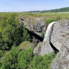 La cascade du Deroc, un lieu idéal pour la baignade, dévale une falaise rocheuse entourée de verdure.