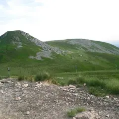 Vue panoramique du Puy de Paillaret, un volcan d'Auvergne aux pentes verdoyantes parsemées de roches.