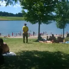 Journée ensoleillée au lac de Naussac, baigneurs et familles profitent de la plage et de l'eau.