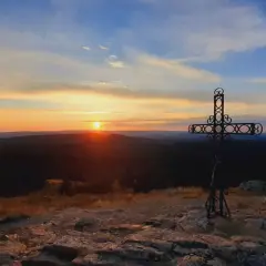 Coucher de soleil sur le moure de la Gardille, avec une croix ornementale veillant sur le paysage.