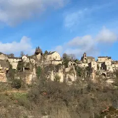 Village perché sur une falaise, un paysage typique du Cantobre Aveyron. Maisons de pierre, église et ciel bleu.
