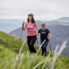 Couple en randonnée en montagne, utilisant des bâtons pour la marche nordique. La différence entre bâton de randonnée et marche nordique est subtile mais importante pour le confort.