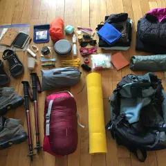 Préparation pour une aventure : chaussures de randonnée, sac de couchage, matelas, vêtements, gourde et accessoires pour savoir comment ranger son sac de randonnée.