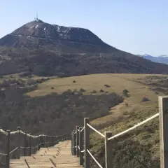 Escalier en bois menant au sommet du puy de Dôme, avec une vue panoramique sur les volcans d'Auvergne.