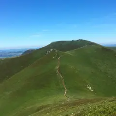 Sentier sinueux menant à la croix Morand, dominant un paysage verdoyant sous un ciel bleu.