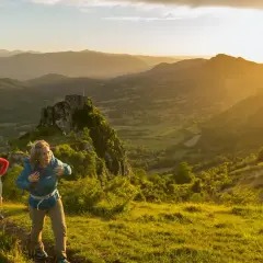 Deux randonneurs sur le sentier des cathares, profitant d'un paysage montagneux baigné par le soleil couchant.