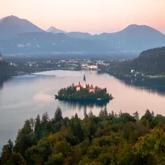 Île avec église et château sur un lac, entouré de montagnes. Un rêve pour visiter la Slovénie.