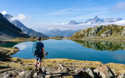 Randonneur contemplant un lac d'altitude aux reflets parfaits, paysage du tour des lacs des 7 Laux.