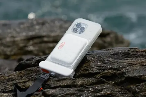 Coque étanche pour téléphone, conforme à la norme IPX8, posée sur des rochers mouillés près de la mer.