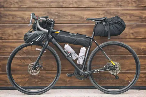 Vélo prêt pour le bikepacking, équipé de sacoches, gourdes et casque. L'aventure vous attend !