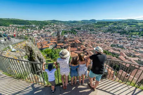 Une famille admire le panorama de la ville. Que voir au Puy en Velay ? La cathédrale et ses toits de tuiles rouges s'étendent à perte de vue.