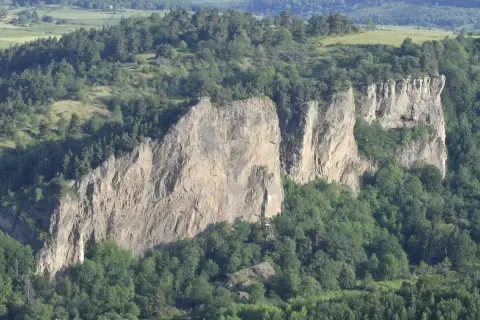 Falaises rocheuses spectaculaires, idéales pour une randonnée à Murol. Végétation luxuriante et paysage vallonné en arrière-plan.