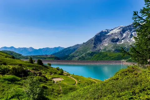 Paysage de montagne spectaculaire avec un lac turquoise et un barrage. Un endroit à voir en Auvergne pour sa beauté naturelle.