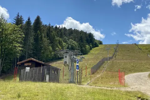 Remontée mécanique au col de Supeyres, avec une cabane en bois et une piste d'été bordée de sapins.