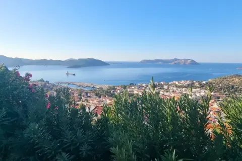 Vue panoramique sur la mer Égée, avec une ville côtière et des îles au loin. Un aperçu de la **voie lycienne**.