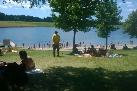 Journée ensoleillée au lac de Naussac, baigneurs et familles profitent de la plage et de l'eau.