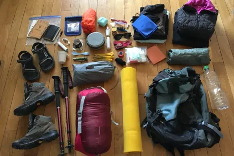 Préparation pour une aventure : chaussures de randonnée, sac de couchage, matelas, vêtements, gourde et accessoires pour savoir comment ranger son sac de randonnée.