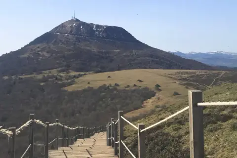 Escalier en bois menant au sommet du puy de Dôme, avec une vue panoramique sur les volcans d'Auvergne.