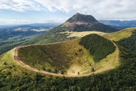 Vue aérienne du cratère du Pariou, un volcan endormi en Auvergne, avec le Puy de Dôme en arrière-plan.