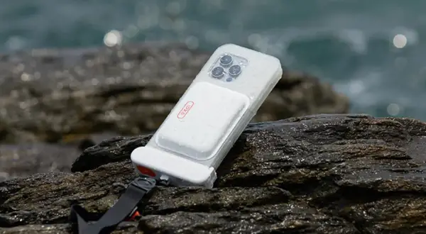 Coque étanche pour téléphone, conforme à la norme IPX8, posée sur des rochers mouillés près de la mer.