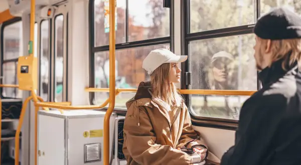 Dans un train, une jeune femme au bonnet blanc regarde par la fenêtre. Le paysage défile, rappelant un voyage en Cantal.