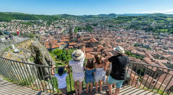 Une famille admire le panorama de la ville. Que voir au Puy en Velay ? La cathédrale et ses toits de tuiles rouges s'étendent à perte de vue.