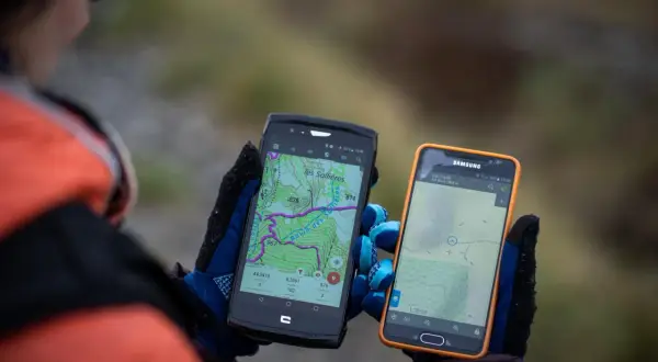 Deux smartphones affichent des cartes topographiques, un **GPS piéton** sur un iPhone et un autre appareil. Idéal pour la randonnée.