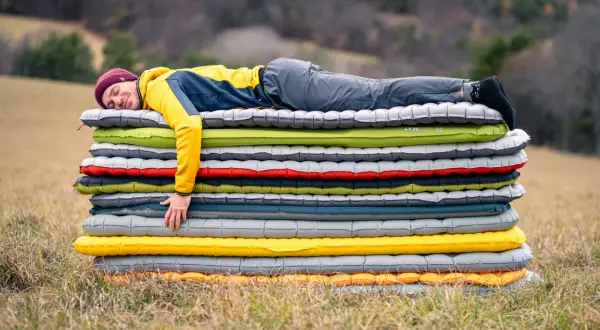 Un homme dort sur une pile de matelas gonflables. Il semble qu'il ait attendu longtemps pour savoir combien de temps laisser gonfler un matelas.