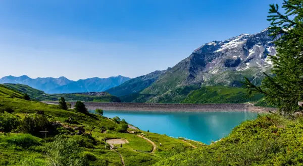 Paysage de montagne spectaculaire avec un lac turquoise et un barrage. Un endroit à voir en Auvergne pour sa beauté naturelle.