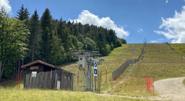 Remontée mécanique au col de Supeyres, avec une cabane en bois et une piste d'été bordée de sapins.