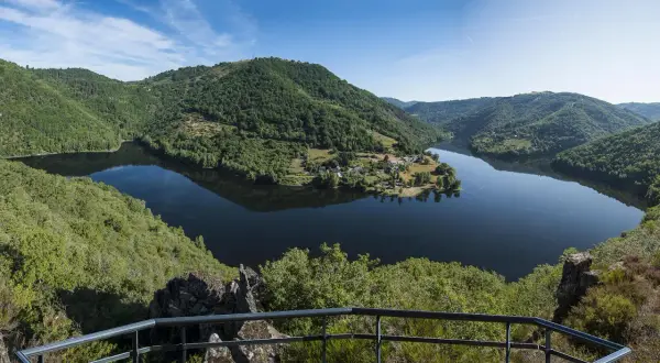 Vue panoramique des gorges de la Truyère, un lac paisible serpente entre des collines verdoyantes. Idéal pour la randonnée.
