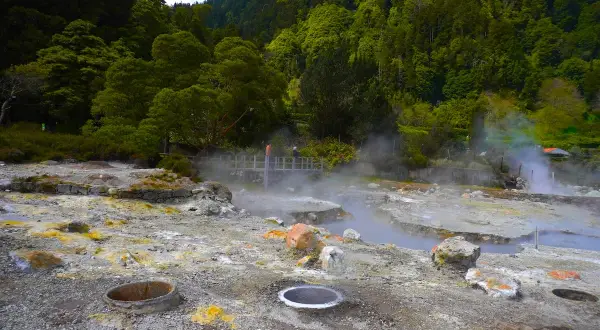 Paysage volcanique des Furnas Açores, avec des fumerolles et des sources chaudes au milieu d'une végétation luxuriante.