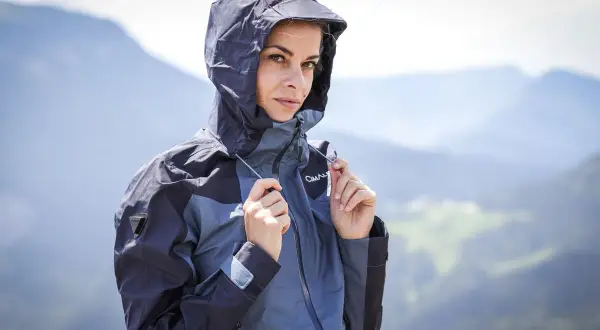 Femme en veste à capuche, prête pour la pluie. Comprendre la différence entre étanche et imperméable est essentiel pour choisir la bonne protection.