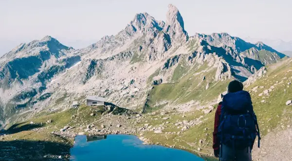 Randonneuse admirant un lac bleu et des montagnes majestueuses, un refuge en vue. Une belle étape du tour du Beaufortain 3 jours.