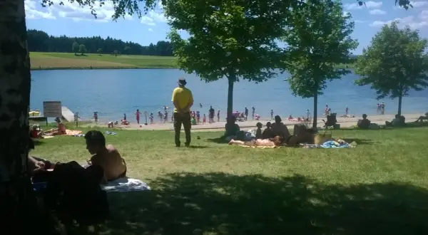 Journée ensoleillée au lac de Naussac, baigneurs et familles profitent de la plage et de l'eau.