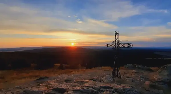 Coucher de soleil sur le moure de la Gardille, avec une croix ornementale veillant sur le paysage.