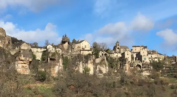 Village perché sur une falaise, un paysage typique du Cantobre Aveyron. Maisons de pierre, église et ciel bleu.