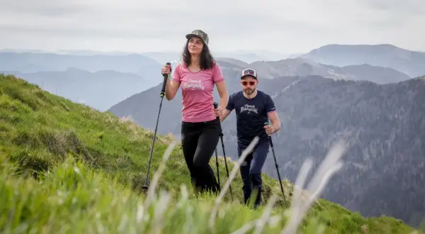 Couple en randonnée en montagne, utilisant des bâtons pour la marche nordique. La différence entre bâton de randonnée et marche nordique est subtile mais importante pour le confort.