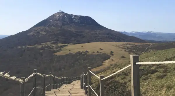 Escalier en bois menant au sommet du puy de Dôme, avec une vue panoramique sur les volcans d'Auvergne.